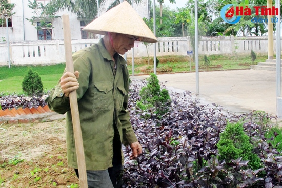 Người phụ nữ tự nguyện dọn dẹp khuôn viên, chăm sóc bồn hoa cây cảnh ở thôn Cây Chanh.